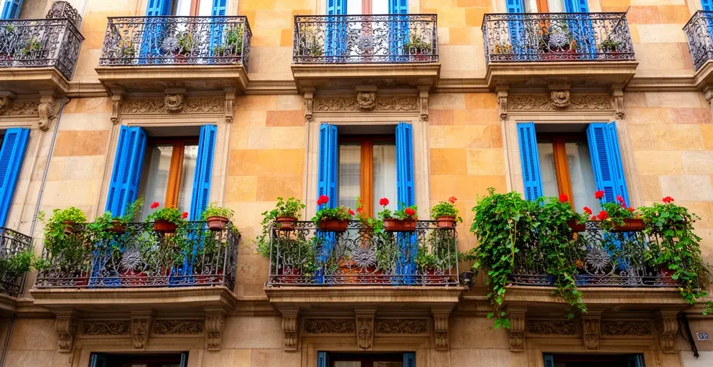 Fachada típica de edificio residencial en Barcelona con balcones y plantas mediterráneas